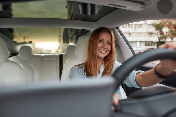 Smiling young caucasian girl sitting on driver seat - Fotó, kép