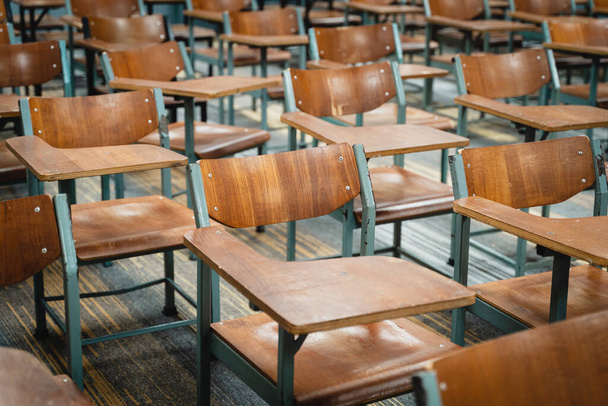 Dřevěné židle pro přednášky uspořádané ve třídě. Prázdná vysokoškolská učebna s mnoha dřevěnými židlemi, ale žádní studenti. Návrat do školy. - Fotografie, Obrázek