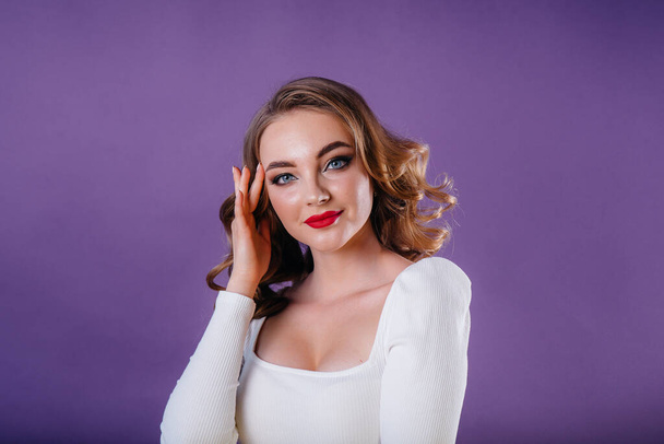 A young beautiful girl shows emotions and smiles in the Studio on a purple background. Girls for advertising - Foto, immagini