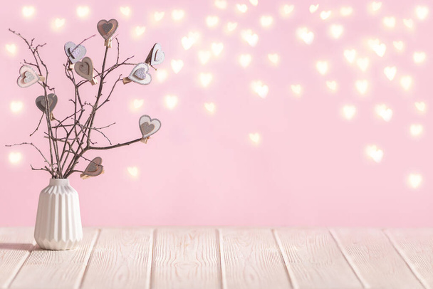 Interior table decoration with branches and hearts in vase with hearts lights on the pink background with copy space - Foto, Bild