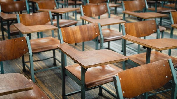 Drewniane krzesła wykładowe rozmieszczone w klasie. Pusta klasa koledżu z wieloma drewnianymi krzesłami wykładowymi, ale bez studentów. Powrót do koncepcji szkoły. - Zdjęcie, obraz