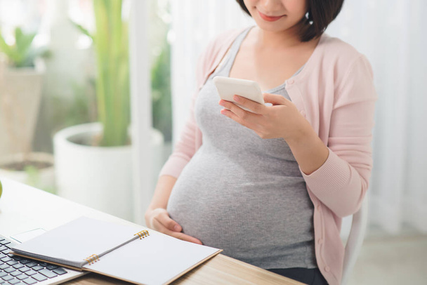 Pregnant Businesswoman Reading Text Message In Office - Photo, Image