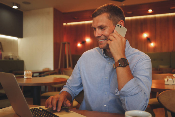 Happy man talking on smartphone in cafe - Foto, afbeelding