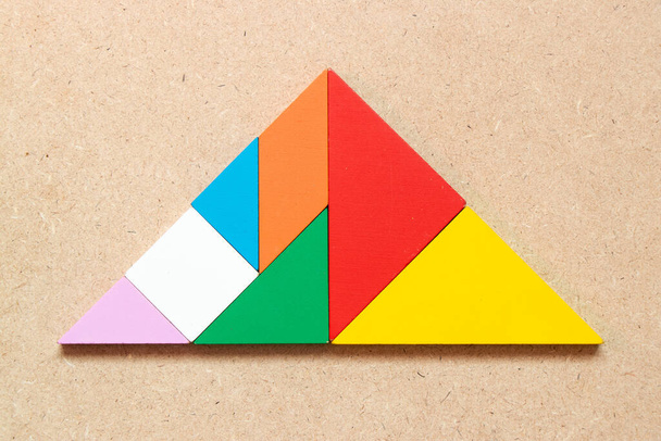 Puzzle couleur tangram en forme de triangle sur fond de bois - Photo, image
