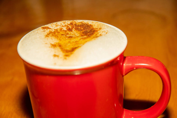 taza roja emiten café y espuma de leche con canela - Foto, imagen
