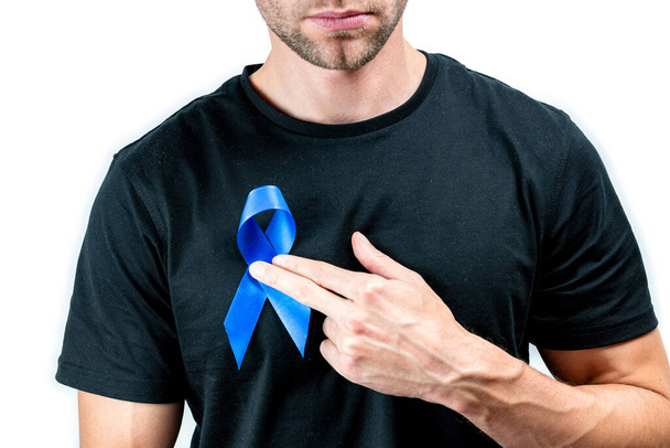 Blue prostate ribbon. Awareness cancer of men health. Hipster men in black shirt with blue ribbon in hands isolated on white background. November and International Mens Day - Photo, Image