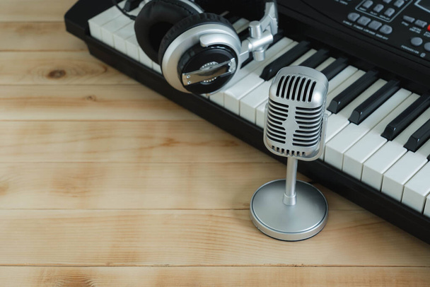 Zenei eszköz koncepció háttér. Közelkép csoport zenei eszközök az ezüst mikrofon, fejhallgató, elektronikus billentyűzet barna fa másolási hely kreatív tervezési szöveg. - Fotó, kép