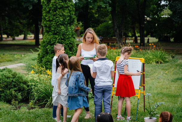 A teacher teaches a class of children in an outdoor Park. Back to school, learning during the pandemic - Fotoğraf, Görsel
