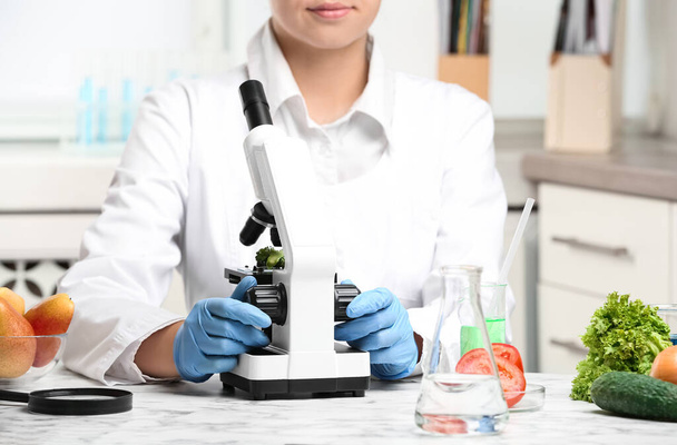 Ученый осматривает брокколи с помощью микроскопа в лаборатории, крупным планом. Выявление яда - Фото, изображение
