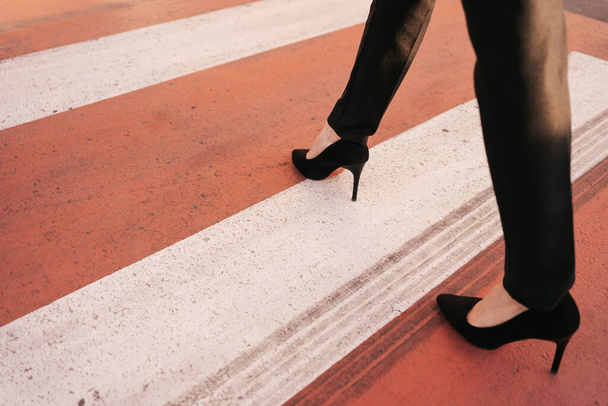 Közelkép nő lábak fekete nadrág és magas dombok cipő séta zebra - Fotó, kép