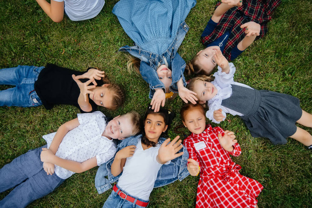 A group of school children lie on the grass in a circle and have fun. Happy childhood - Photo, image