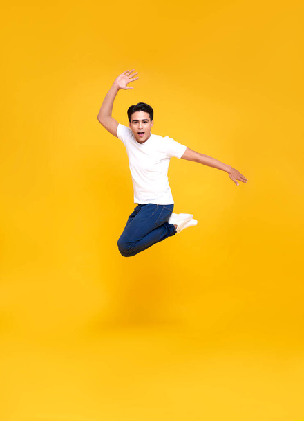 Young happy handsome Asian man jumping isolated over yellow background. - Foto, Imagen