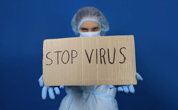 Dokter vrouw in beschermende masker houden poster Stop virus - Foto, afbeelding