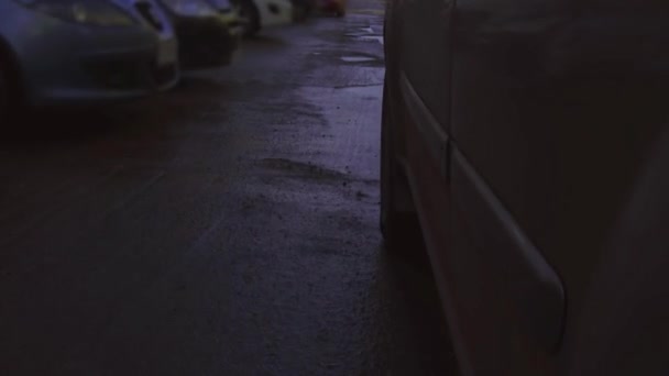 Κοντινό πλάνο του τροχού αυτοκινήτου σε ένα δρόμο σε πολύ κακή κατάσταση με μεγάλες λακκούβες γεμάτες από βρώμικες λιμνούλες με νερό βροχής - Πλάνα, βίντεο