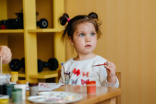 A cute little girl is playing and painting in her room. Recreation and entertainment - Photo, Image