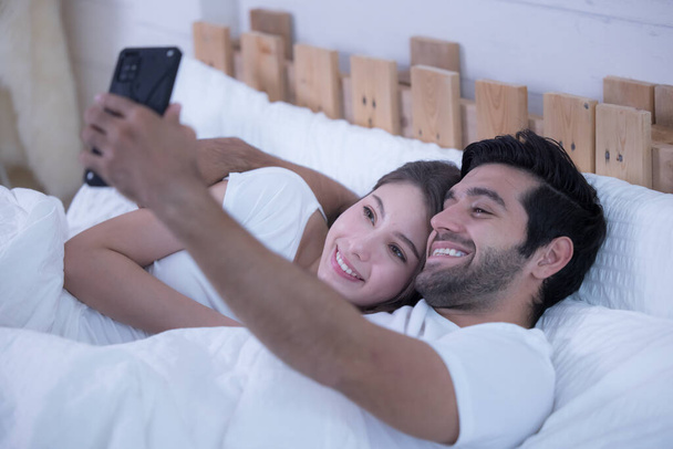 Casal jovem em uma cama com telefones celulares - Foto, Imagem