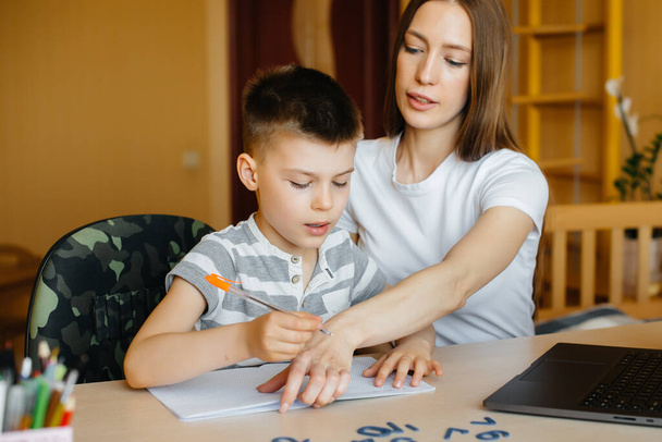 A mother and her child are engaged in distance learning at home in front of the computer. Stay at home, training - Foto, afbeelding