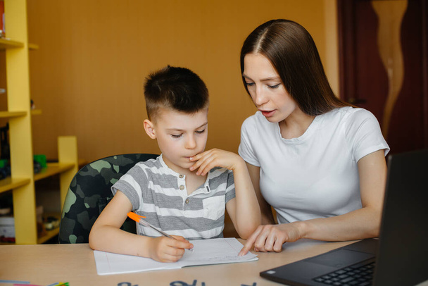 A mother and her child are engaged in distance learning at home in front of the computer. Stay at home, training - Φωτογραφία, εικόνα