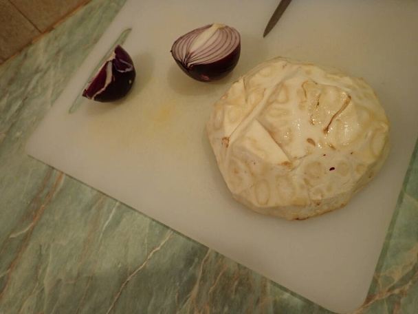 Zwiebeln und Keller auf weißem Brett in der Küche schneiden - Foto, Bild