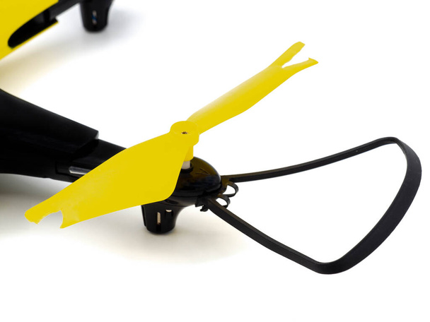 A broken black and yellow flight drone. Damage to the quadcopter propeller from impact. Photo isolated on a white background. The concept of repair in the workshop. - Fotografie, Obrázek