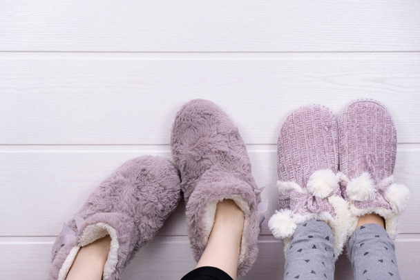 girls legs raised up in warm house slippers, on a gray background - Фото, изображение