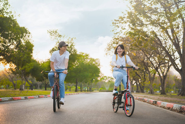 İlkbahar, mutlu ve neşeli bir Asyalı çiftin bisiklet sürmesi konseptiyle geliyor. - Fotoğraf, Görsel