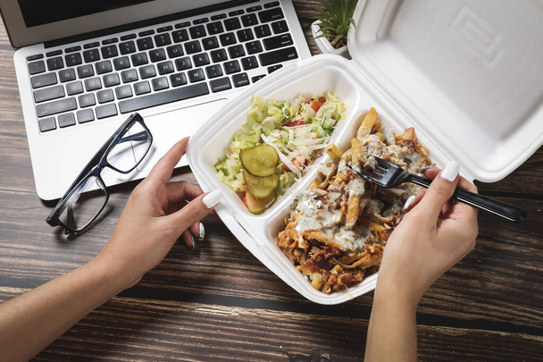 Vrouw handen opent voedsel container op houten tafel in de buurt van laptop. Fast food levering thuis. Ik eet thuis zakenlunch. Werk vanuit huis. Afstandswerk - Foto, afbeelding
