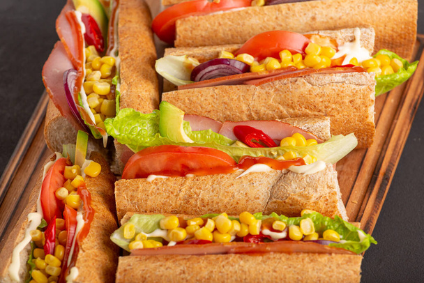 Lahodné sendviče se šunkovou zeleninou a omáčkou zblízka na tmavém stole - Fotografie, Obrázek