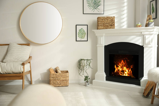 Bright living room interior with artificial fireplace and firewood in basket - Photo, image