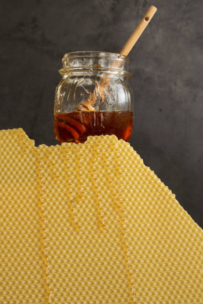 Tarro con miel cruda y peine de abeja sobre fondo oscuro, concepto de nutrición saludable - Foto, imagen