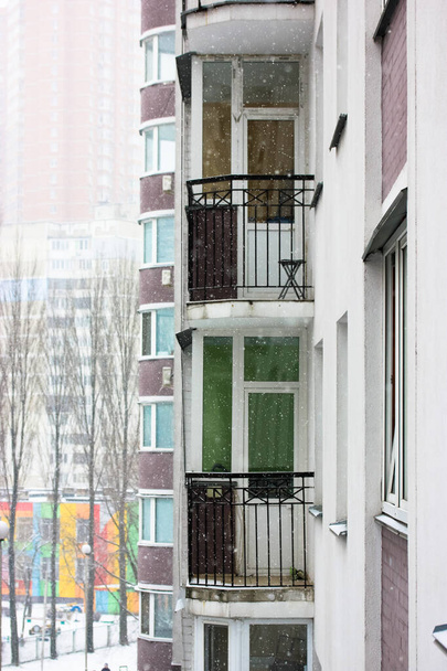 Fasáda obytné budovy, bílá stěna, okna a neprosklené balkony ve velkém městě, sníh v zimě. Kyjev, Evropa. - Fotografie, Obrázek