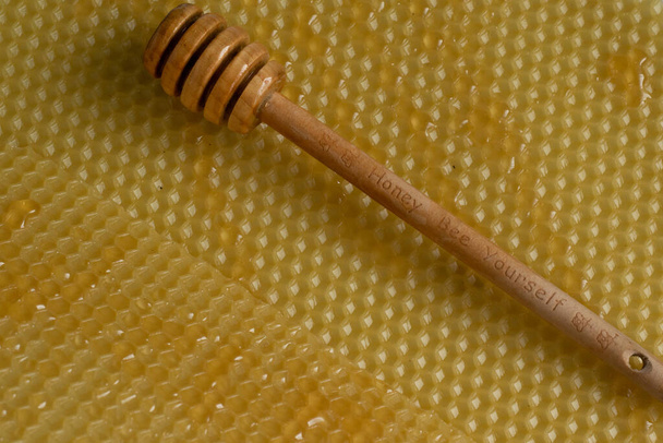 Közelkép a mézes kanál nyers méz méhsejt háttér, egészséges táplálkozás koncepció - Fotó, kép