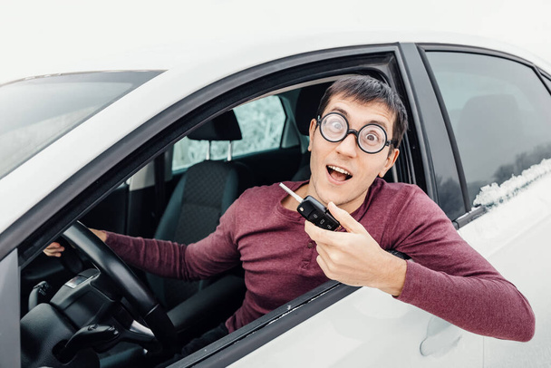Legrační řidič v brýlích s klíčkem od auta a s úsměvem do kamery. Koncept nového řidiče a pojištění - Fotografie, Obrázek