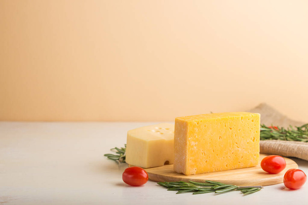 Various types of cheese with rosemary and tomatoes on wooden board on a white and orange background and linen textile. Side view, close up, copy space, selective focus. - Foto, immagini