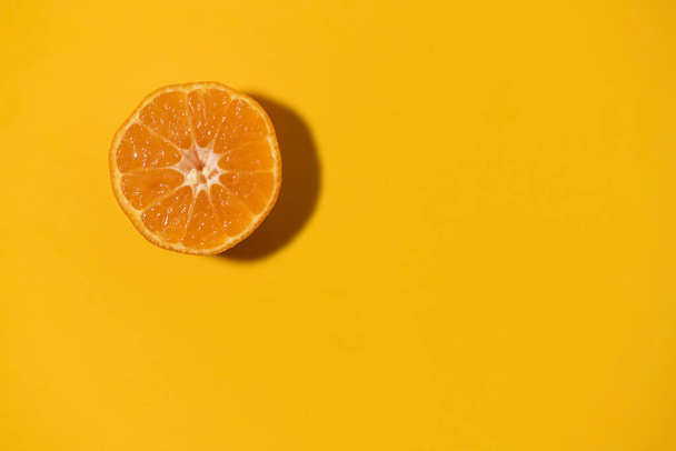Half cut clementine tangerine isolated on orange color background. Copy space. - Фото, зображення