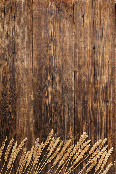 Old wooden table with spikelets wheat bakery. - Foto, afbeelding