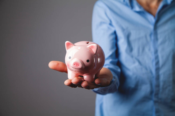 Human hand protecting a piggy bank - Foto, afbeelding