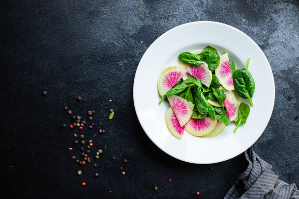 Görögdinnye retek saláta kínai daikon diéta friss szeletek rózsaszín gyümölcs zöldségek, zöld levelek arugula spenót saláta egészséges étel snack felülnézet másolás tér élelmiszer háttér  - Fotó, kép