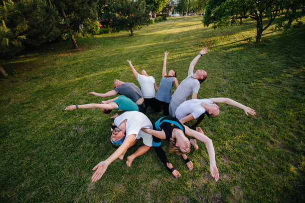 A group of people do yoga in a circle in the open air during sunset. Healthy lifestyle, meditation and Wellness - Zdjęcie, obraz