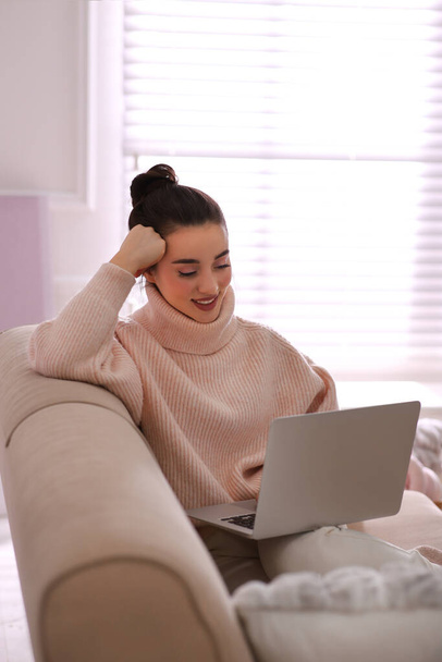 Beautiful young woman with laptop relaxing at home. Cozy atmosphere - Foto, Imagen