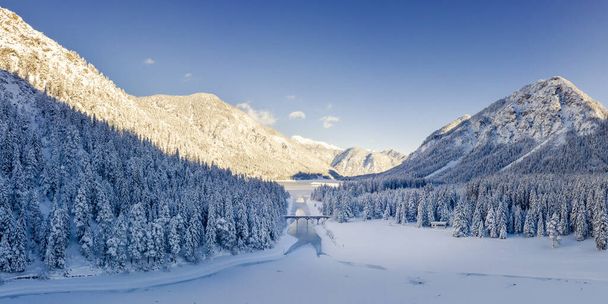 冬は雪に覆われた冬にはプランゼー湖とハイテルヴァンゲルゼー湖の間の運河橋、そしてチロル山脈の真ん中の凍った水 - 写真・画像