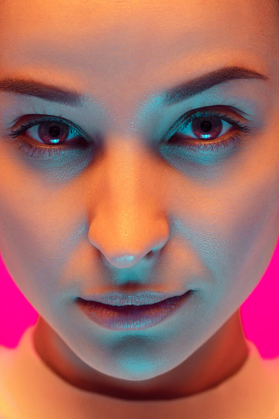 Caucasian beautiful womans portrait isolated on pink studio background in multicolored neon light - Foto, Imagem
