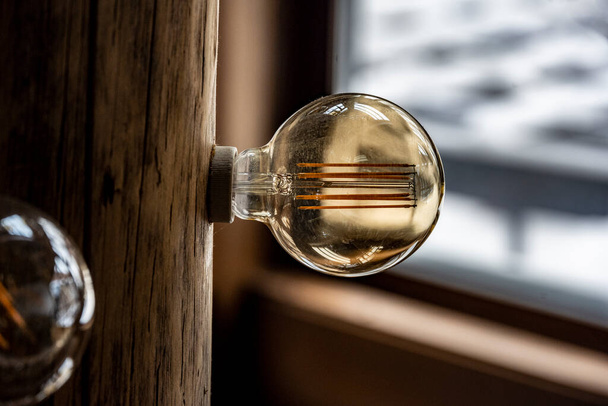 bombillas incandescentes vintage en el interior de una casa de campo de invierno con elementos de madera - Foto, imagen