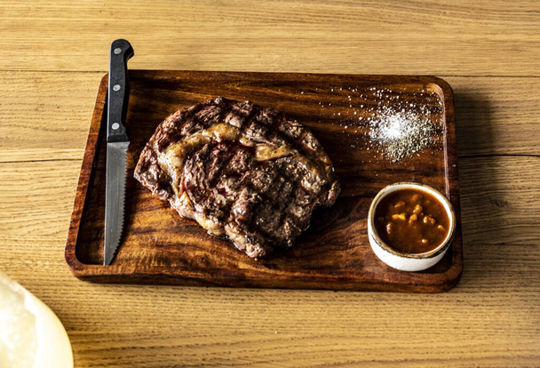 csendélet egy nagy darab grillezett hússal egy fa tányéron - Fotó, kép