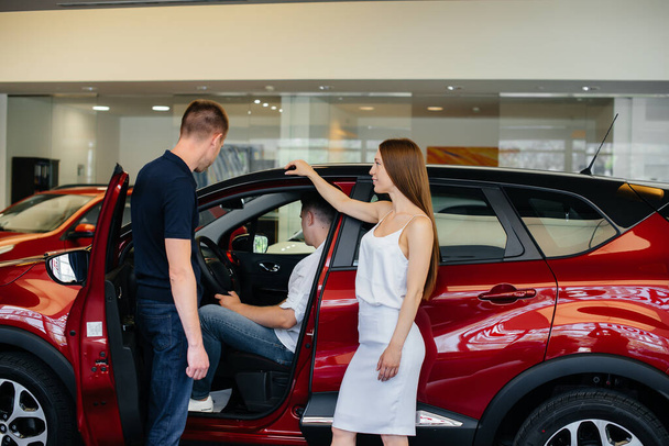 A happy young couple chooses and buys a new car at a car dealership. Buying a new car - Valokuva, kuva