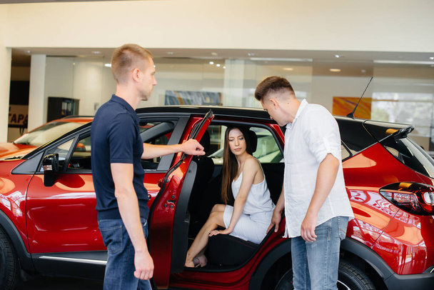 A happy young couple chooses and buys a new car at a car dealership. Buying a new car - Foto, imagen