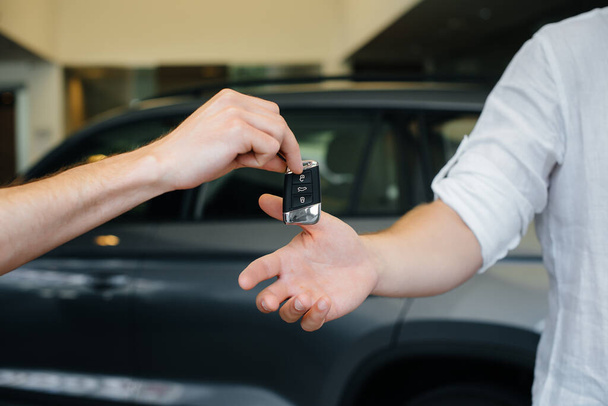 The seller passes the keys to a new car to a young family. Buying a new car - Foto, Imagem