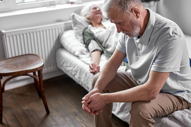 depressed man sits near his sick wife - Foto, immagini