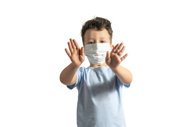 Konzept der Coronavirus-Quarantäne. Kind trägt medizinische Schutzmaske während Grippeviren und macht Stoppgeste. COVID-19. Kleiner weißer Junge macht Stoppschild mit seinen Händen, isoliert auf weiß - Foto, Bild