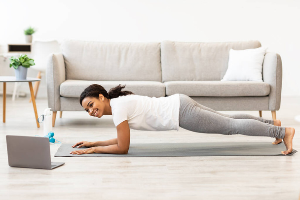 Mujer negra haciendo ejercicio en casa viendo tutorial en el portátil - Foto, Imagen